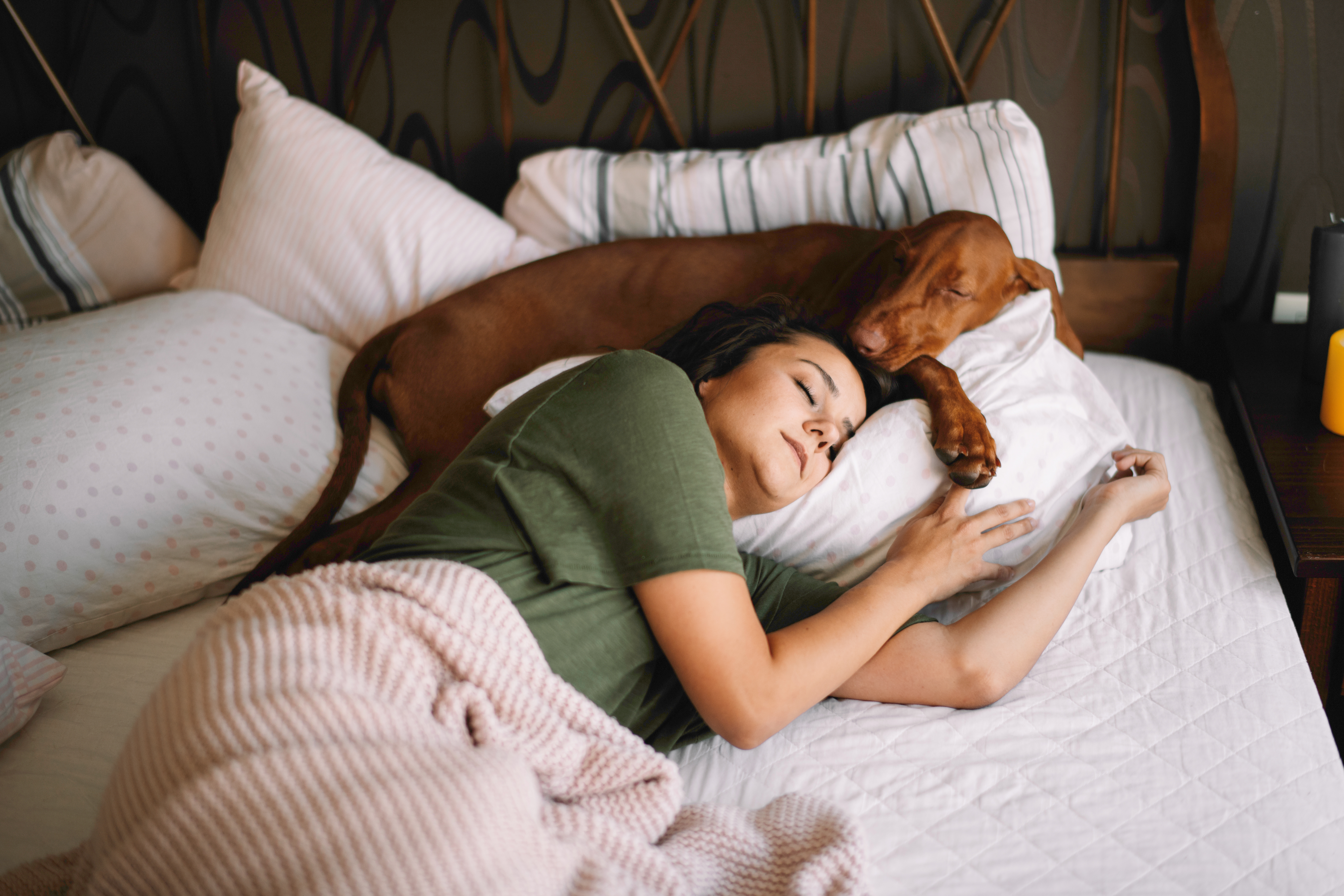 Woman relaxing in bed with her dog, symbolizing calm mornings and mindful rest.