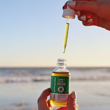 A bottle of organic CBD oil perched on a rock
