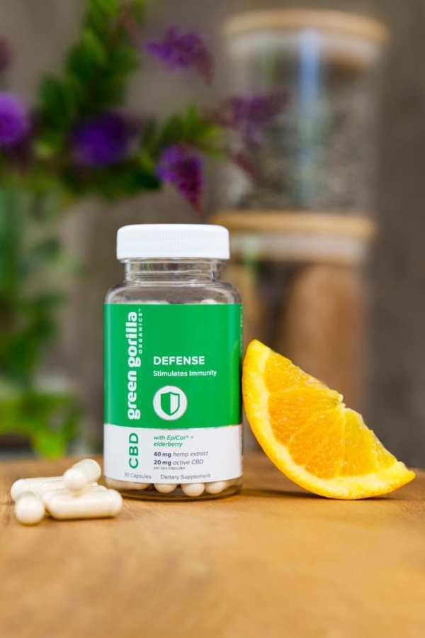 A bottle of organic CBD edible capsules next to an orange slice