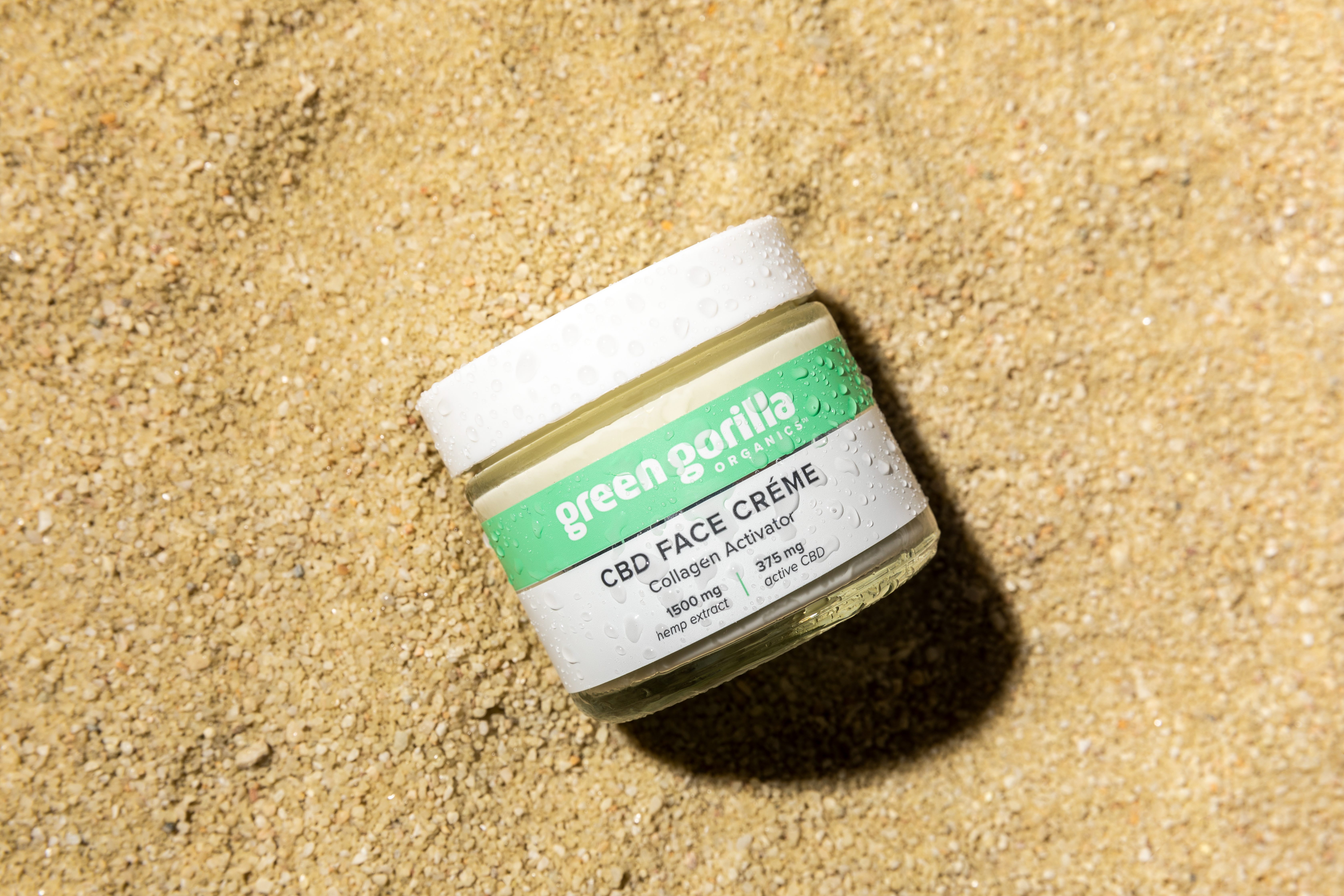 A wet jar of CBD Face Crème on sand