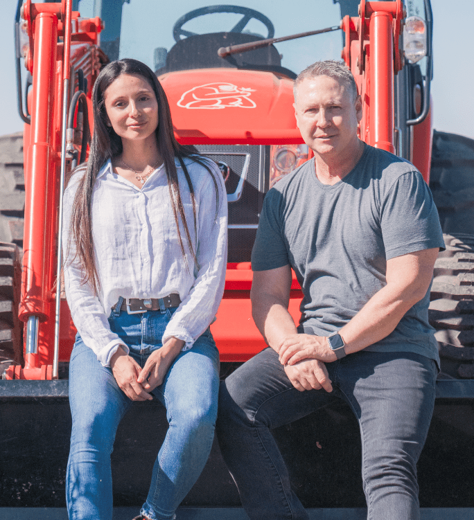 Founders Steven and Katherine Guevara Saxton sitting on a tractor in a hemp field.