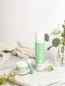 Green Gorilla™ body lotion, face cream, and lip balm on a marble counter with flowers and towels.