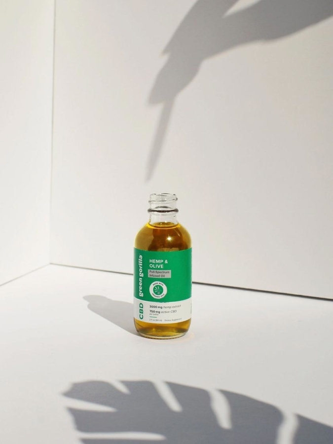 An open bottle of CBD oil with the shadow of someone holding a dropper
