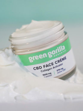 Open jar of Green Gorilla™ CBD Face Crème in pile of loose white crème