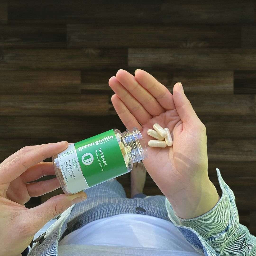 Person pouring capsules from a bottle of Green Gorilla™ CBD oil immune system Defense bottle into their hand