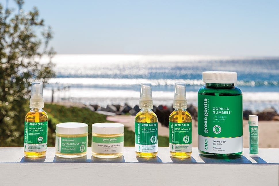 Seven Green Gorilla™ CBD products arranged on a fence in front of a beach