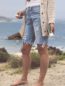Bottom half of a woman carrying a bottle of Green Gorilla™ CBD oil for pets in front of a beach landscape